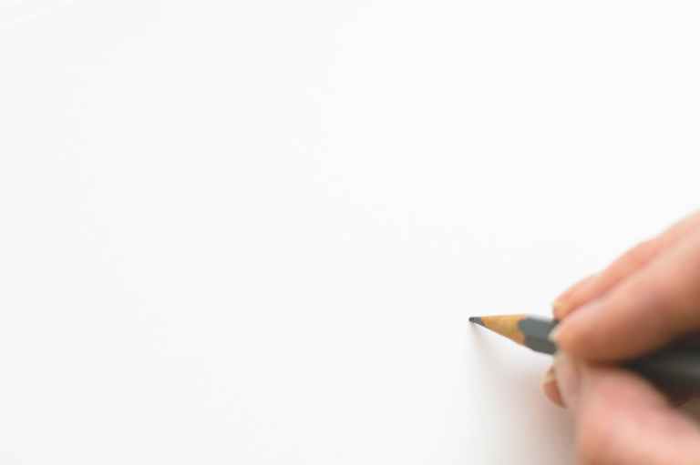 close up of hand holding pencil over white background