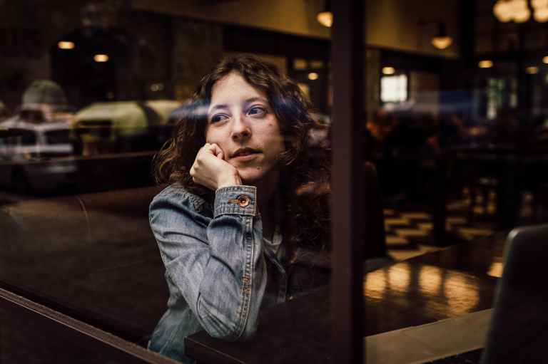 woman wearing blue denim jacket putting her right arm on her cheek